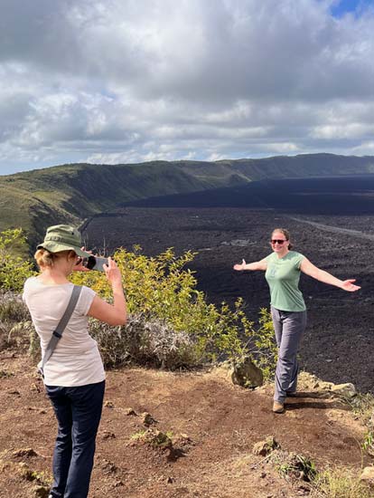 Personas tomándose una foto con el cráter del volcán Sierra Negra.